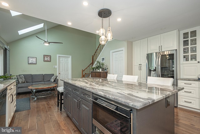 kitchen with dark wood-style flooring, light stone countertops, a kitchen bar, a center island, and white cabinetry