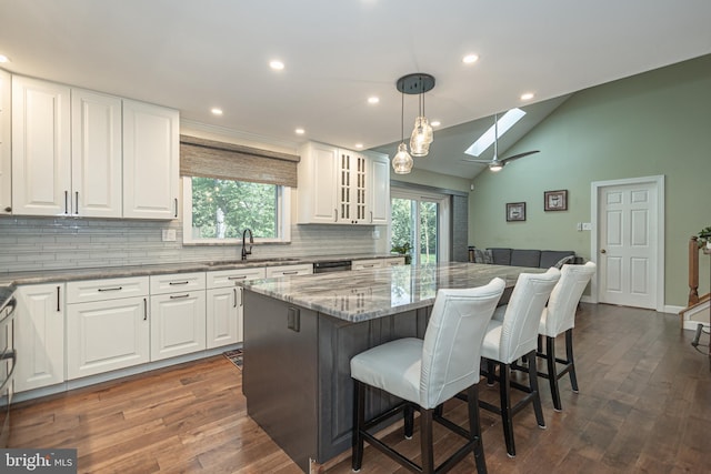 kitchen featuring backsplash, white cabinetry, a skylight, and a sink