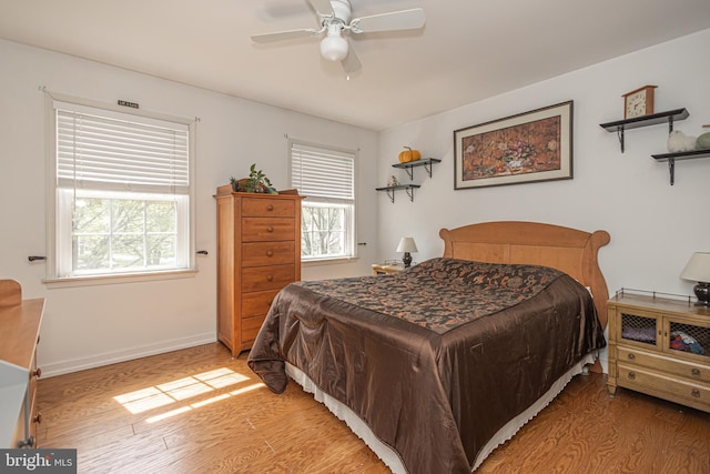 bedroom with a ceiling fan, baseboards, and light wood-style floors