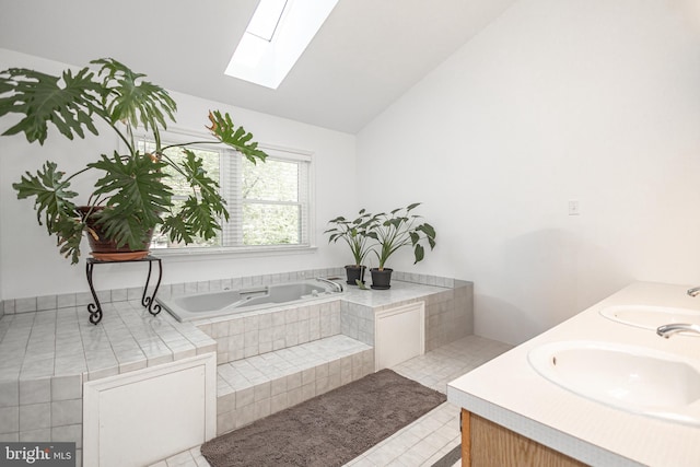 bathroom with double vanity, a sink, a bath, and vaulted ceiling with skylight
