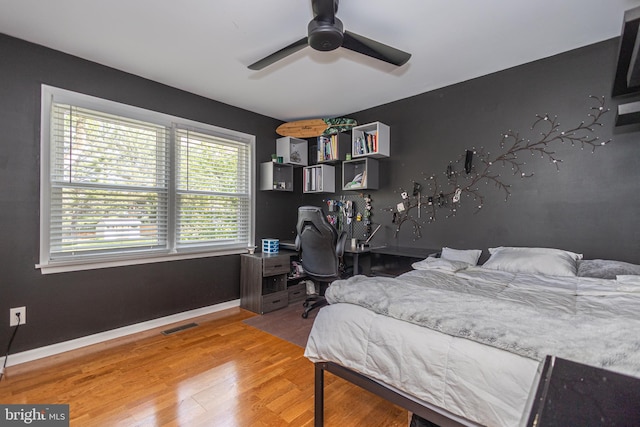 bedroom with baseboards, ceiling fan, wood finished floors, and visible vents
