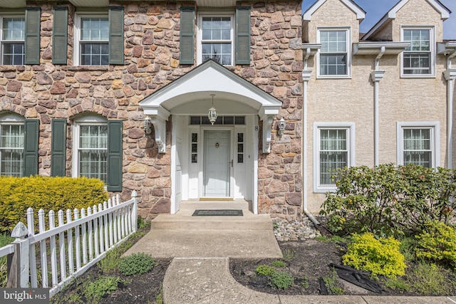 entrance to property with fence and stone siding