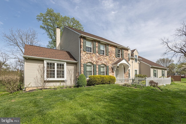colonial inspired home featuring a chimney, fence, a front yard, and stone siding