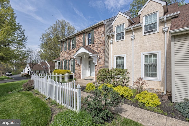 view of front of property with fence, stone siding, and a front lawn