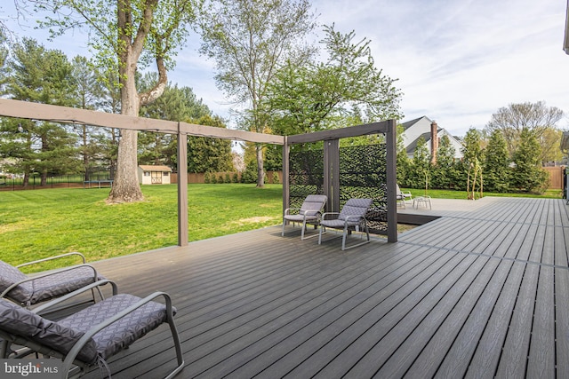 wooden deck featuring an outdoor structure, a fenced backyard, and a lawn