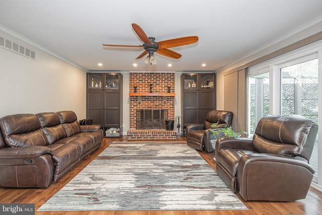 living room featuring ornamental molding, a ceiling fan, wood finished floors, and visible vents
