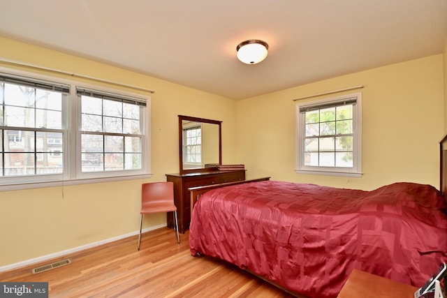 bedroom with baseboards, wood finished floors, and visible vents
