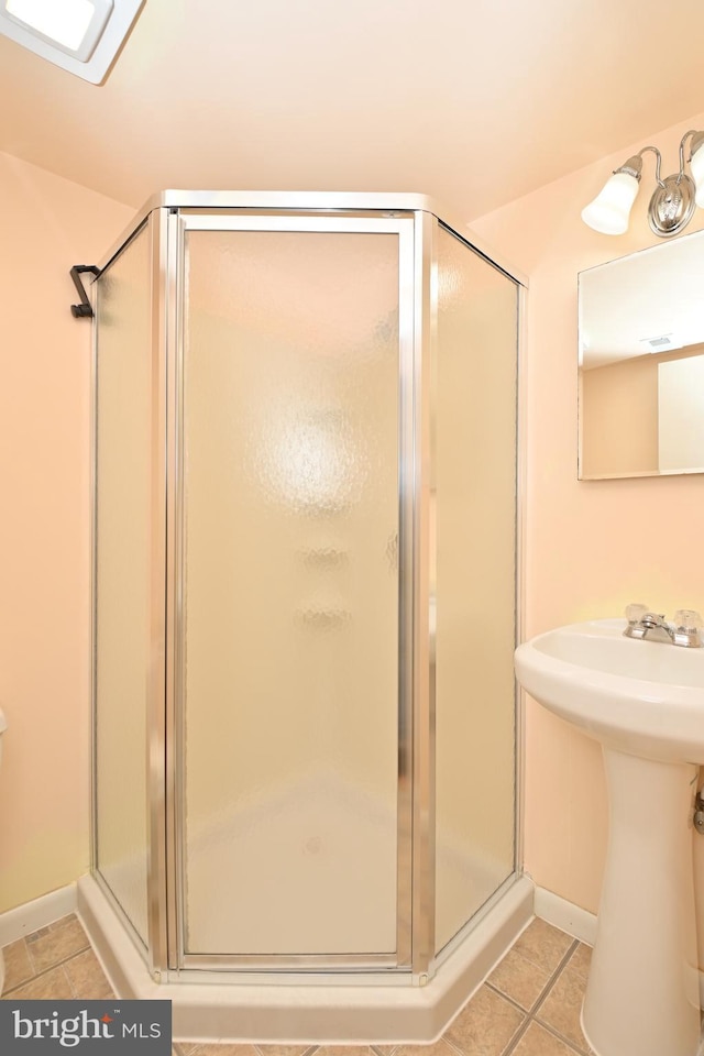 full bath with tile patterned flooring, a sink, baseboards, and a shower stall