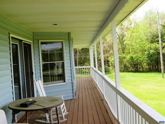 wooden terrace with covered porch and a yard