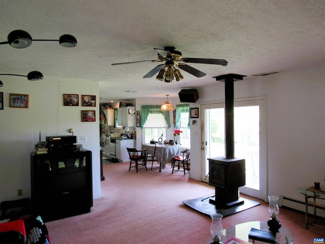 interior space with baseboard heating, a textured ceiling, ceiling fan, and a wood stove