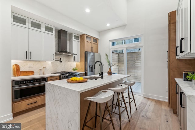 1104 N Bodine St, Philadelphia, PA 19123 - kitchen with decorative backsplash, wall chimney exhaust hood, a sink, stainless steel appliances, and light wood-style flooring
