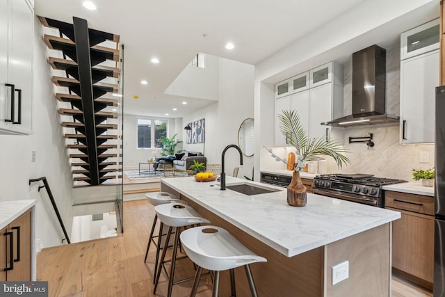 1104 N Bodine St, Philadelphia, PA 19123 - kitchen featuring light stone countertops, a center island with sink, stainless steel gas stove, a sink, and wall chimney exhaust hood
