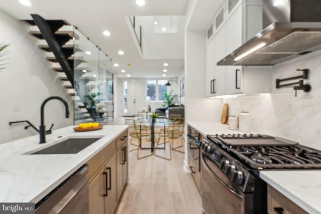 1104 N Bodine St, Philadelphia, PA 19123 - kitchen with light stone countertops, a sink, black range with gas stovetop, wall chimney exhaust hood, and stainless steel dishwasher