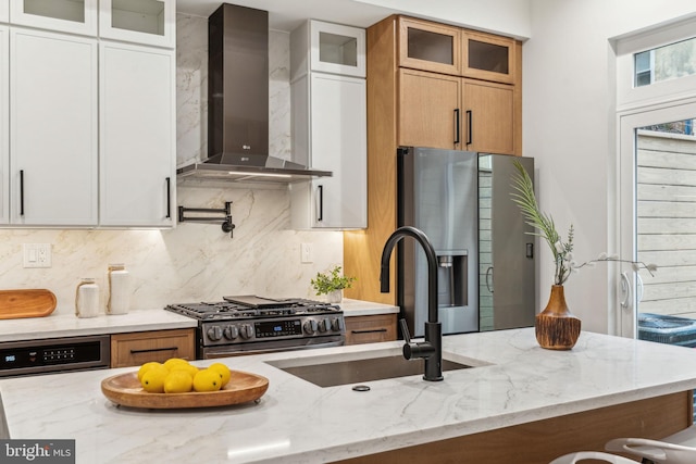 1104 N Bodine St, Philadelphia, PA 19123 - kitchen featuring light stone countertops, appliances with stainless steel finishes, a sink, wall chimney exhaust hood, and tasteful backsplash