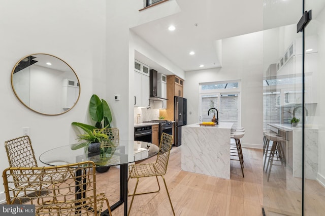 1104 N Bodine St, Philadelphia, PA 19123 - kitchen with a kitchen island with sink, appliances with stainless steel finishes, light wood-type flooring, a sink, and wall chimney exhaust hood