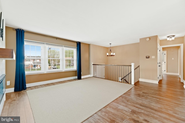 unfurnished room featuring light wood-type flooring, baseboards, and a chandelier