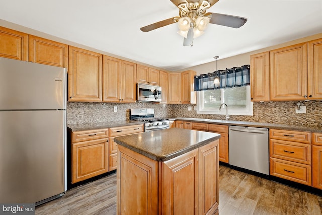 kitchen with light wood-style flooring, appliances with stainless steel finishes, and tasteful backsplash