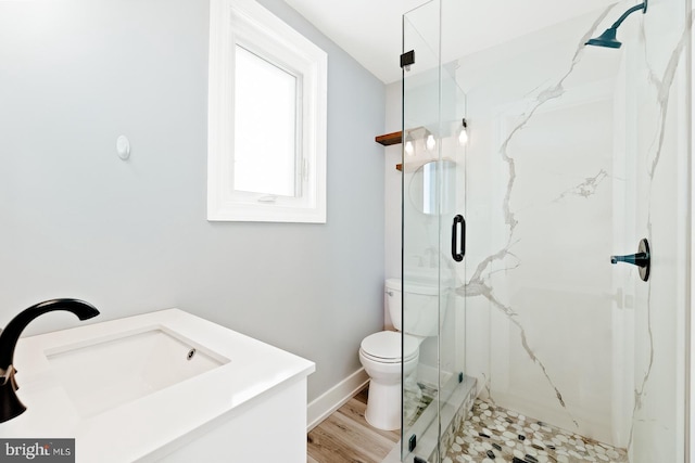 full bathroom with wood finished floors, toilet, baseboards, a sink, and a marble finish shower
