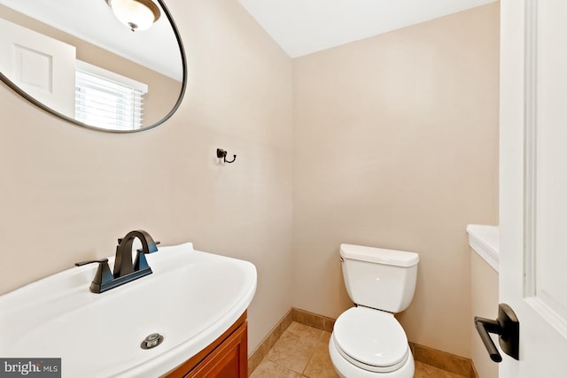 bathroom featuring baseboards, a sink, tile patterned flooring, and toilet