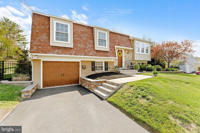 bi-level home featuring a garage, fence, a front yard, brick siding, and driveway