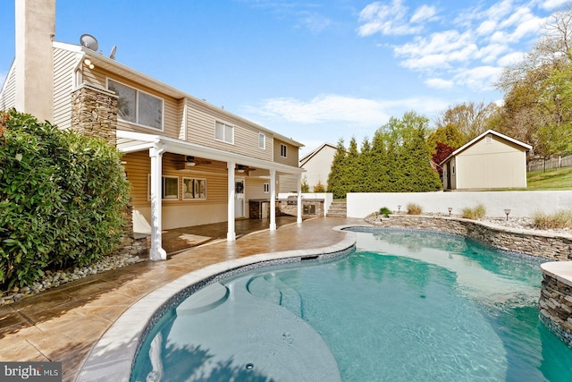 view of pool with ceiling fan, a storage shed, a patio area, fence, and an outdoor structure