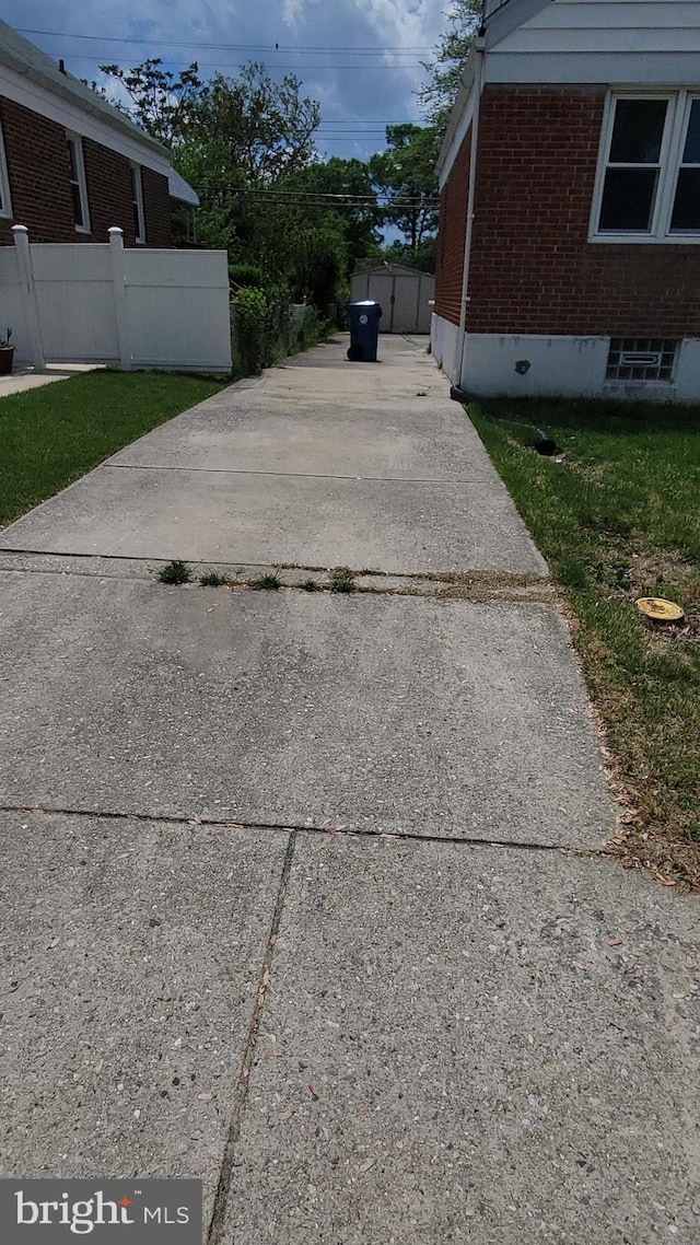 view of side of home featuring brick siding, fence, and concrete driveway