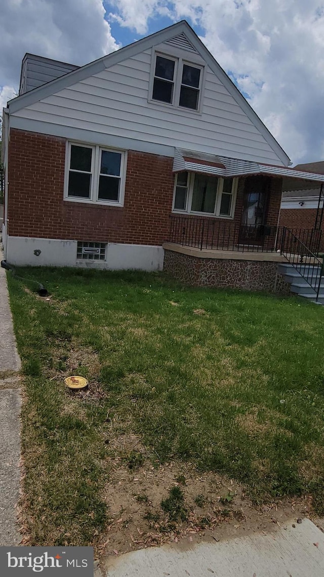 view of front of property with brick siding, a front lawn, and covered porch