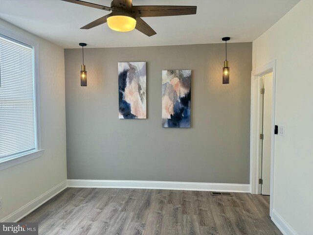 unfurnished room featuring baseboards, ceiling fan, wood finished floors, and visible vents