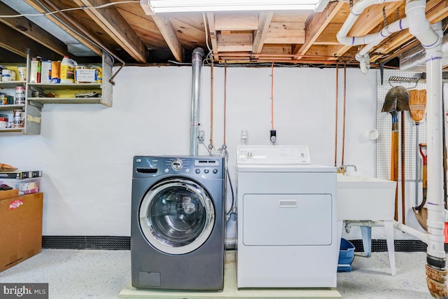 washroom featuring separate washer and dryer, laundry area, and a sink