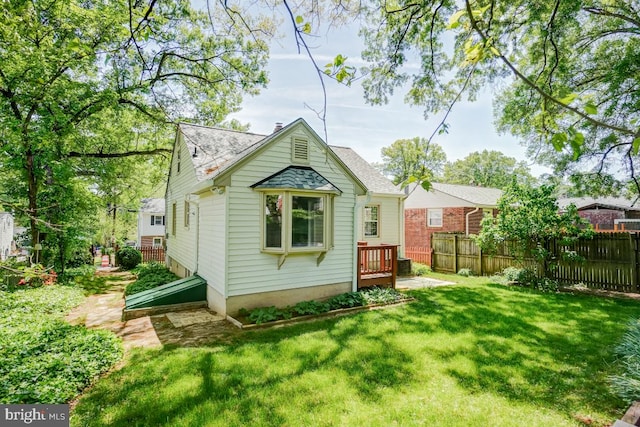 rear view of house featuring a lawn and fence