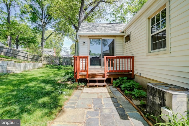 exterior space with central air condition unit, a fenced backyard, and a wooden deck