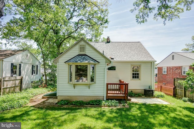 back of house with a lawn, fence, a chimney, and cooling unit