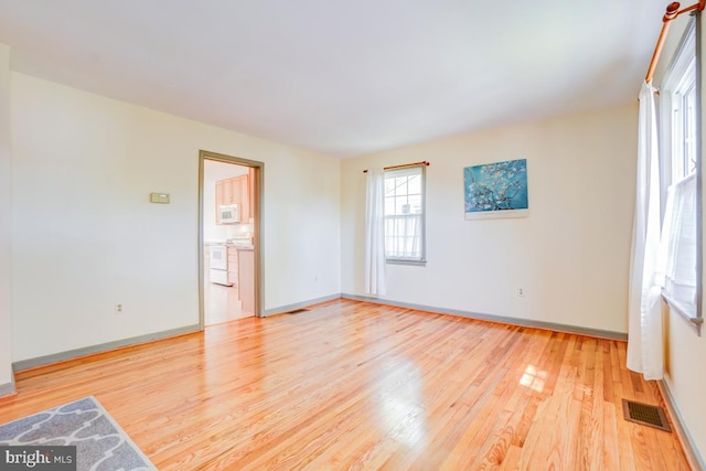 unfurnished room featuring baseboards, visible vents, and light wood-style flooring