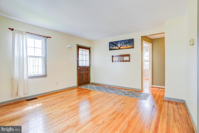 foyer entrance featuring baseboards, light wood finished floors, and visible vents