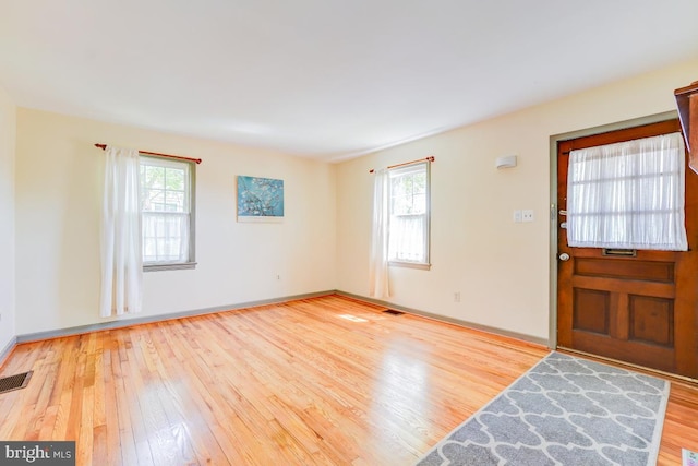 entryway with plenty of natural light, baseboards, wood finished floors, and visible vents