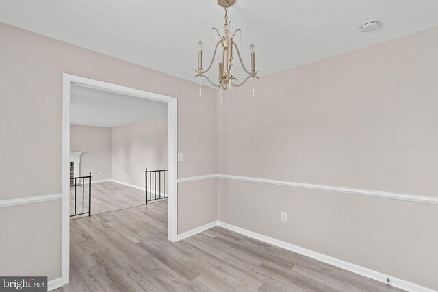 unfurnished dining area with baseboards, wood finished floors, and a chandelier