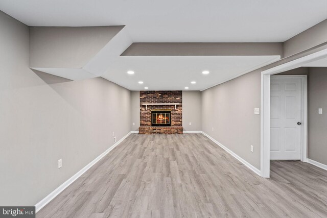 unfurnished living room featuring baseboards, a fireplace, recessed lighting, and light wood-style flooring