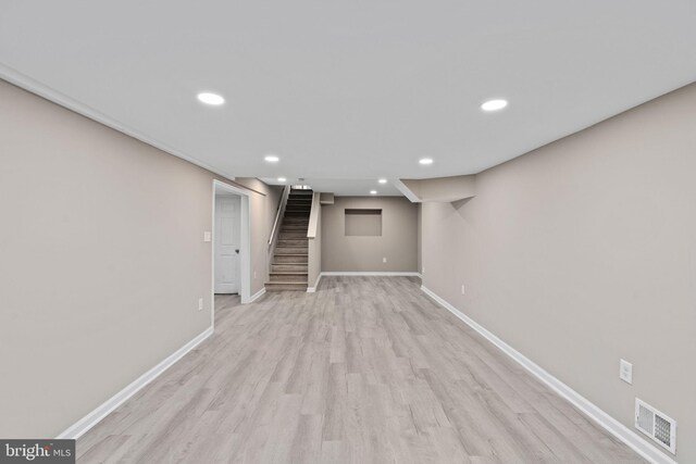 finished below grade area featuring visible vents, stairs, baseboards, recessed lighting, and light wood-type flooring