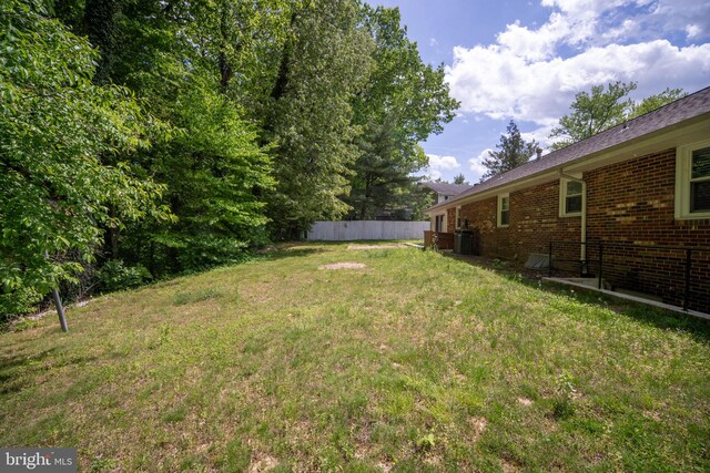 view of yard featuring central AC unit and fence