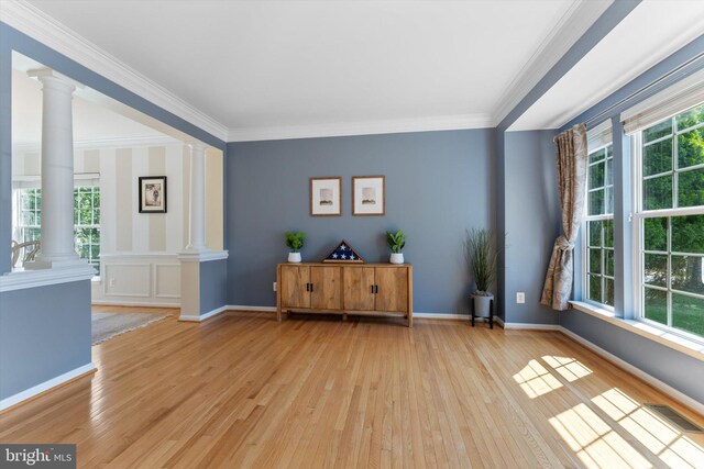living area featuring visible vents, ornamental molding, light wood-style floors, baseboards, and ornate columns