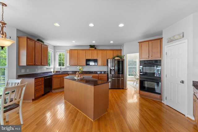 kitchen featuring a kitchen island, a sink, black appliances, light wood finished floors, and recessed lighting