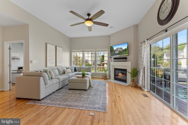 living room featuring visible vents, a fireplace with flush hearth, ceiling fan, and wood finished floors