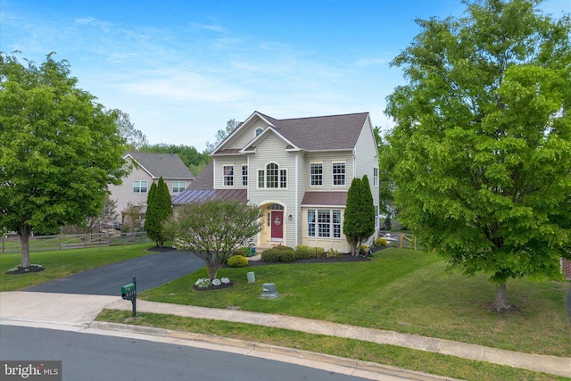 view of front facade featuring a standing seam roof, metal roof, a front yard, fence, and aphalt driveway