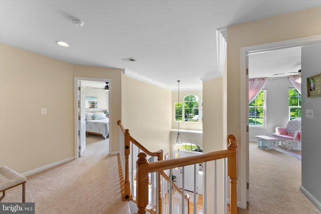 hallway featuring crown molding, light colored carpet, baseboards, an upstairs landing, and visible vents