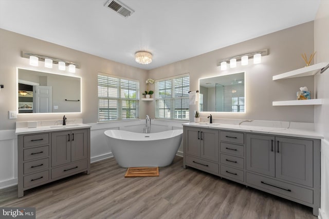 bathroom featuring visible vents, a freestanding bath, a sink, and wood finished floors