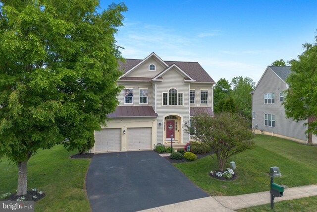 traditional-style home with aphalt driveway, a garage, a front yard, a standing seam roof, and metal roof