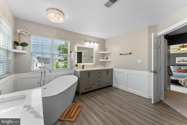 ensuite bathroom with visible vents, connected bathroom, wood finished floors, and a wainscoted wall