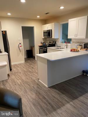 25 Bucknell Rd, Somers Point, NJ 08244 - kitchen featuring stainless steel appliances, a sink, a peninsula, white cabinetry, and recessed lighting