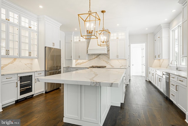 kitchen featuring beverage cooler, white cabinetry, a center island, and stainless steel appliances