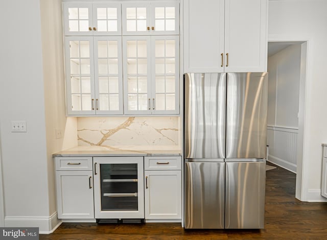 bar with tasteful backsplash, freestanding refrigerator, dark wood-style floors, and beverage cooler